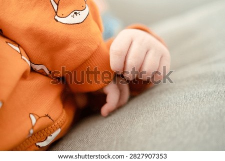 Newborn infant tiny hand with delicate fingers on soft fabric closeup. Baby palm reveals tender, fragile skin in peaceful indoor moment, capturing innocent vulnerability in soft light