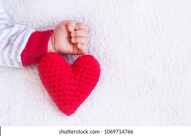 Newborn Little Baby  Macro Arm / Hand In White Blanket With Knitting Red Heart 
