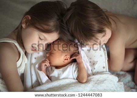 Similar – Image, Stock Photo Happy little girl holding doll and cookie while woman playing with a boy over the bed. Weekend family leisure time concept.