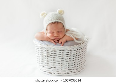 Newborn Photoshoot Baby Sleeping In The Basket On White Background In Knitted White Bear Hat