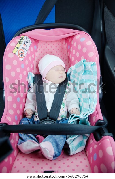 Newborn sleeping in car seat.Safety concept. Infant\
baby girl. secure driving with children. Baby care lifestyle. Cute\
baby sleeping in car.