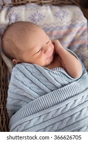 newborn sleeps in a basket in a knitted shawl