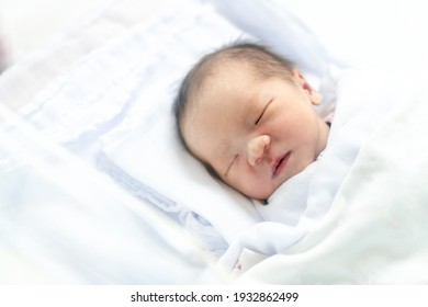 The Newborn Is Wrapped In A White Diaper In A Baby Crib In A Hospital Nursery Room.