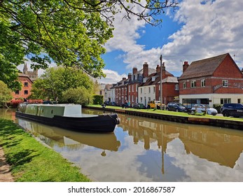 Newbury,Berkshire-UK 05-18-21  A beautiful view in Newbury of the  Kennet and Avon Canal. A man is navigating a barge while the buildings along the bank reflect in the water