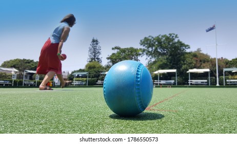 Newcastle, Australia - Feb 2020: View Of The Blue Lawn Bowls Balls On Green Synthetic Lawn With Female Bowler In Action From Behind. Lawn Bowling Is A Outdoor Sport At Australia