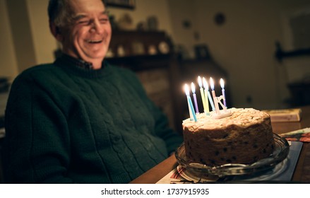 NEWCASTLE UPON TYNE, ENGLAND, UK - NOVEMBER 24, 2018: A Senior Adult Male Siting Back Laughing While Enjoying His Fruit Birthday Cake With Lit Candles.