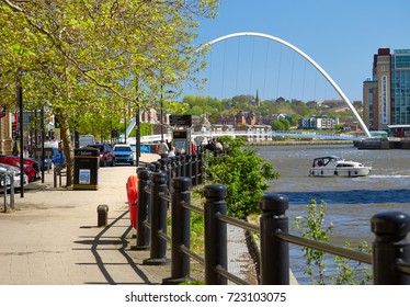 NEWCASTLE UPON TYNE, ENGLAND, UK - MAY 17, 2017: Pedestrians on Newcastle Quayside and a boat on the river Tyne.