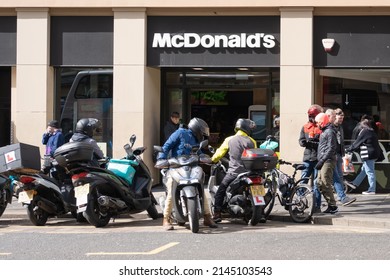 Newcastle Upon Tyne, UK - April 9th, 2022: Gig Economy. Motorcycle And Cycle Food Delivery Couriers Gather Outside A Branch Of McDonalds Awaiting Work.