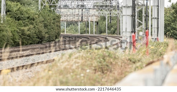 Newcastle-under-Lyme, Staffordshire-united kingdom\
April, 14, 2022 Outdoor diminishing perspective view of curve\
railway track lines without train and mess complex electric cables\
and poles