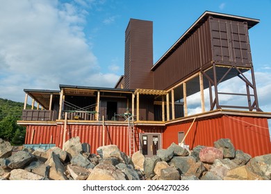 Newfoundland, Canada-October 2021: The Exterior Construction Of A Hotel Using Shipping Containers As Modular Construction. Recycled Brown And Orange Metal Ocean Sea Cans Stacked To Build A New House.