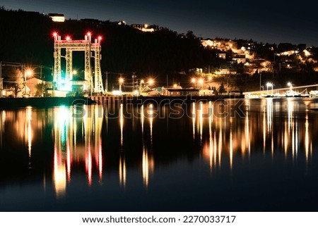 Newfoundland night long exposure scene of the town of Placentia with street lights and the Sir Ambrose Shea Bridge reflecting on the ocean in Canada.