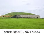 Newgrange Neolithic Tomb in Ireland with Lush Green Grass and Stone Structure