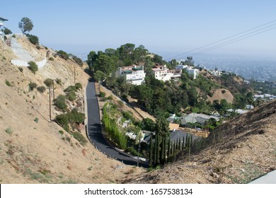 Newly Asphalted Road, High Up In The Hills Of West Hollywood, With Homes On Both Sides, On A Sunny Summer Day, With A Blue Sky.