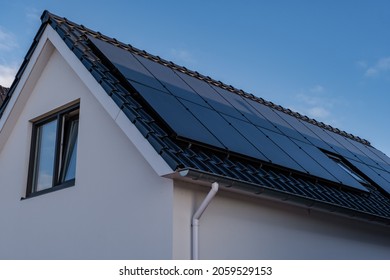 Newly build houses with solar panels attached on the roof against a sunny sky Close up of new building with black solar panels. Zonnepanelen, Zonne energie, Translation: Solar panel, Sun Energy
