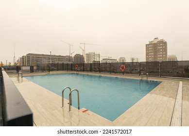 A newly built rectangular community pool in a new area of the city on a torrential rainy day