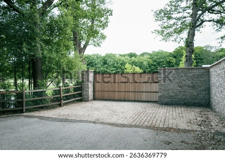 Newly completed automatic sliding front gate seen at the entrance to a newly completed mansion in rural England. The house behind the gate is a new generation of eco friendly houses.