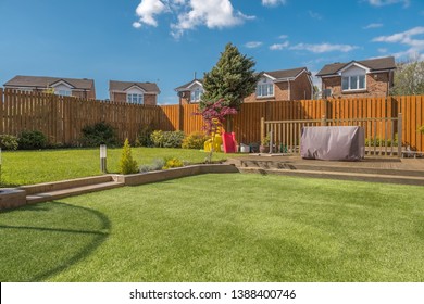 A newly completed and replanted landscaped garden with mixure of artificial and natural sown grass, borders planted, a new decking patio and garden ornaments surrounded by new erected wooden fencing. 