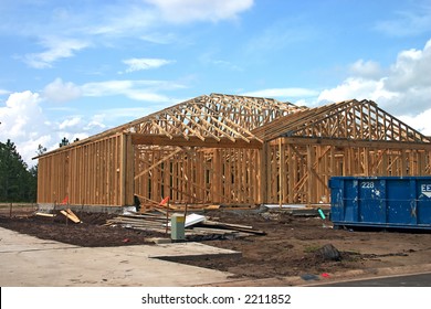 Newly Framed Home With Trusses And Construction Debris And Dumpster