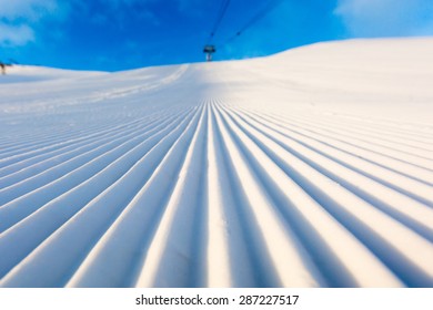 Newly groomed snow on ski slope at ski resort on a sunny winter day.