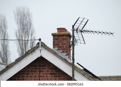 Newly Installed Home TV Antenna Seen Attached To A Large Bungalow's Apex Roof, Which Also Shows A Hooked Up Telephone Cable.