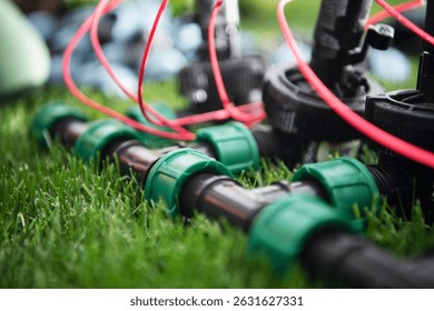 Newly installed irrigation system components are arranged on lush green turf. The focus is on pipes and valves, showing the detailed setup for efficient watering in a residential garden.