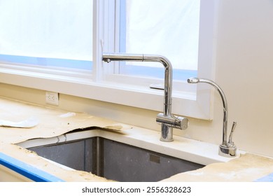 Newly installed modern kitchen sink shines in natural light, highlighting its sleek faucet countertop edges. - Powered by Shutterstock