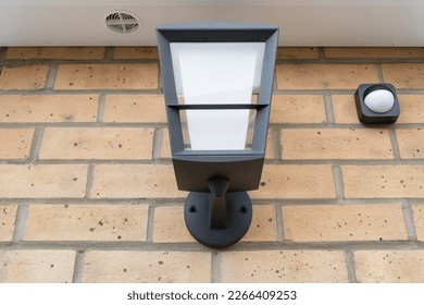 Newly installed multi-colour outdoor smart light seen together with a wireless PIR detector. - Shutterstock ID 2266409253