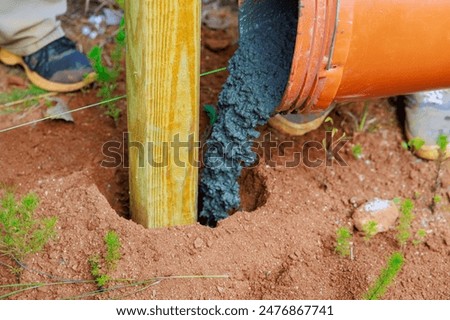 Newly installed timber fencing wooden fence posts are poured with concrete