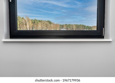 Newly installed white conglomerate window sill inside the room, on the gray wall, visible forest and sky outside the window. - Shutterstock ID 1967179936