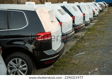 Newly made passenger cars – MPV, crossover, SUV parked in a row among other manufacturer units before sale. Dusk light. Car side rear.