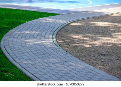 Newly Made Pathway, Fence And Gates To Outdoor Basketball Court In Park. Abstract, Blurry Background Of Boys Playing Basketball 