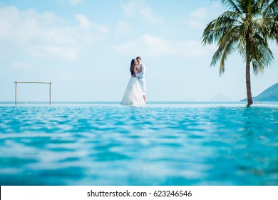 Newly married couple after wedding in luxury resort. Romantic bride and groom relaxing near swimming pool and sea. Honeymoon. Tropical country.