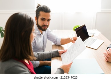 Newly married couple in their 30s signing the mortgage papers at an agent's office - Shutterstock ID 2126349023