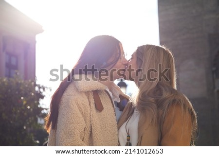Newly married lesbian couple on a honeymoon in a city. The women are showing their love in public by walking around the city and kissing each other. Concept lgtb, equality and rights.