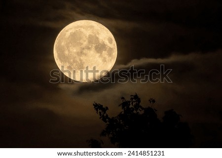 The newly risen Supermoon breaks through the clouds