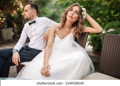 Newlywed coupe sitting on a sofa angry at each other in a middle of an argument. Young couple problem concept outdoor.