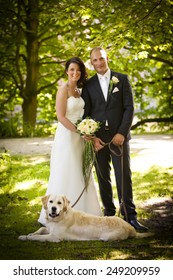 newlywed couple with bouquet and dog after wedding