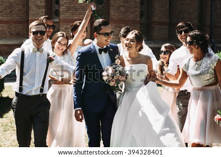 Newlywed couple, bridesmaids & groomsmen having fun outdoors