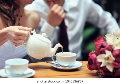 A newlywed couple drinking hot coffee or tea with sweet dessert in warm cozy cafe with wedding bouquet on the table. Atmoshere of happiness of new family and love tenderness - Powered by Shutterstock