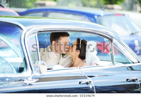 newlywed\
couple, groom  and bride,  kissing in\
car
