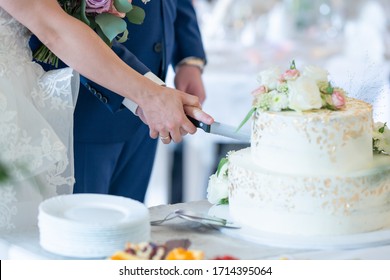 The Newlyweds Cut The Wedding Cake. Hands Are Holding A Knife.