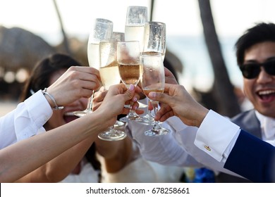 Newlyweds and friends clang their glasses standing outside