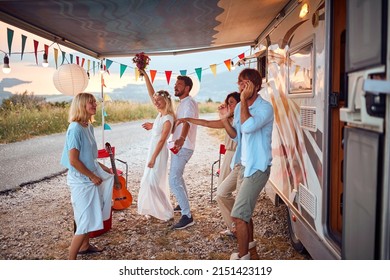 Newlyweds and friends dancing in front of decorated camper rv. Celebration of newlywed couple. Wedding ceremony, love, nature concept
