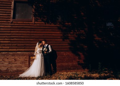 Newlyweds Groom And Bride Near Log House In Autumn