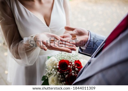 the newlyweds hold wedding rings on the lodon on their wedding day