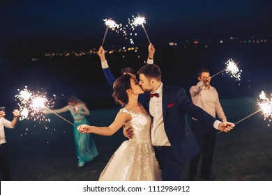 The newlyweds kiss and hold the sparkler