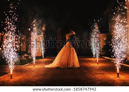 Newlyweds kiss on the background of a pyrotechnic show, fireworks fountains