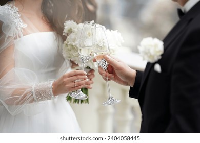 The newlyweds raise a celebratory toast with glasses of white champagne. Wedding celebration. - Powered by Shutterstock