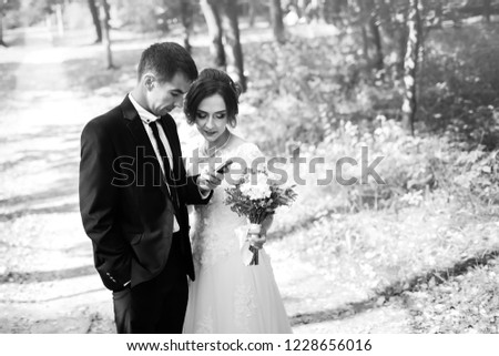 Newlyweds read a congratulatory message in the smartphone from distant relatives. Happy wedding couple. Bride and groom use phone in the park. Black and white photo