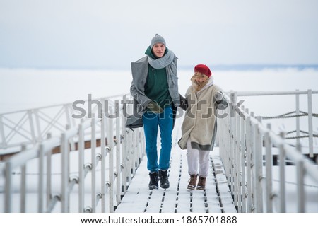 Newlyweds spend their honeymoon in the village, on a snow-covered lake, walking along the pier.
